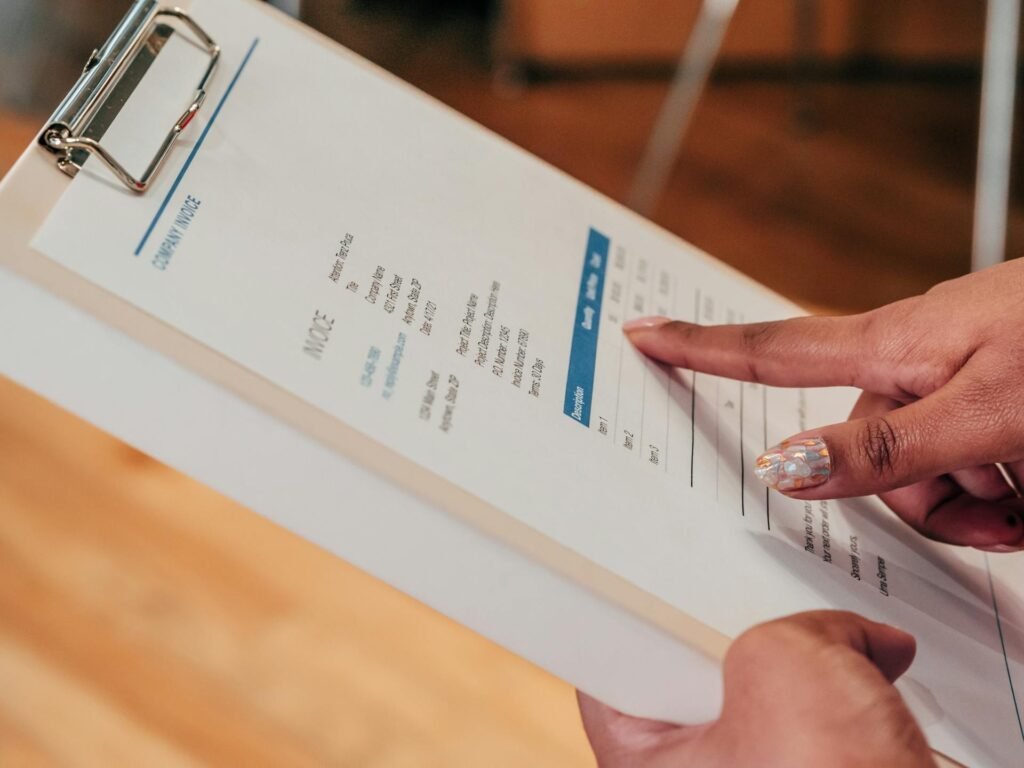 A close-up of someone pointing to an item on a clipboarded invoice