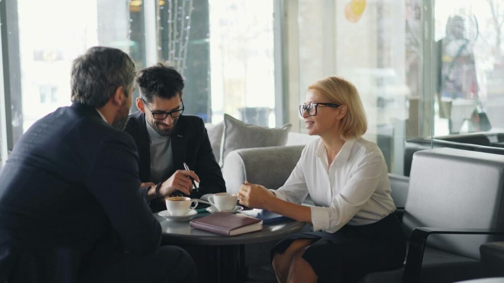 A consultant sits down with two clients having a meeting over coffee discussing the best accounting software for small consulting businesses