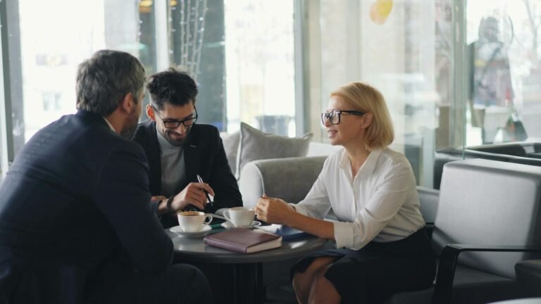 A consultant sits down with two clients having a meeting over coffee discussing the best accounting software for small consulting businesses