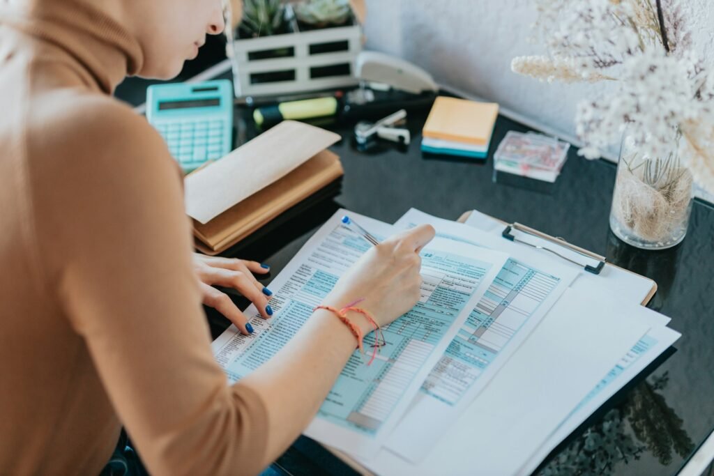 An over-the-shoulder shot of a female freelancer filling in her IRS tax forms at her desk