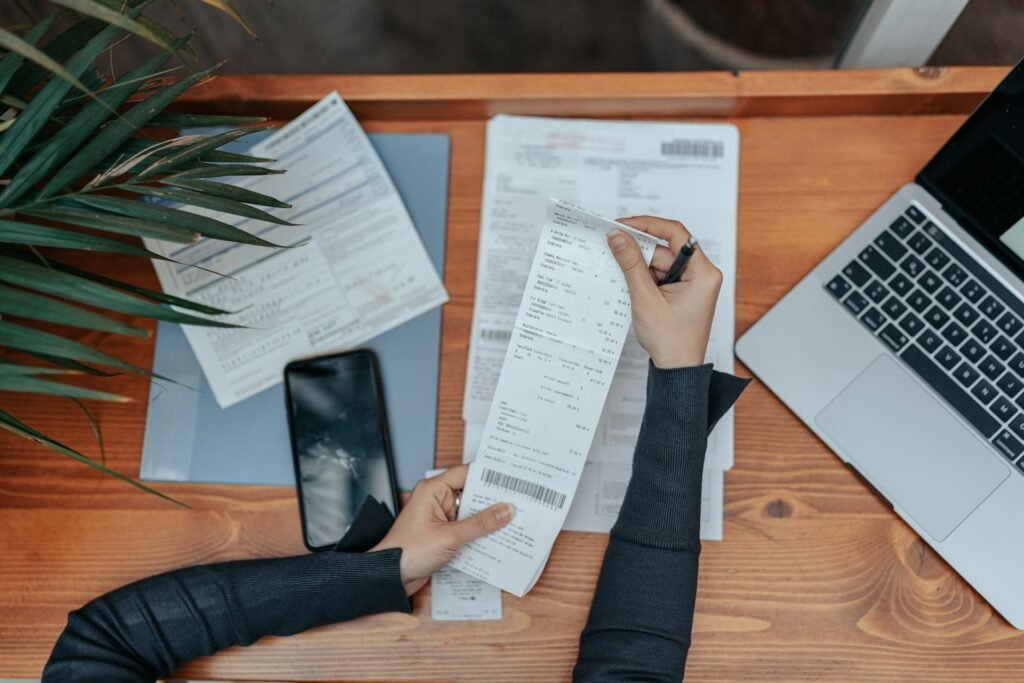 A top-down view of a desk where a freelancer is looking at a receipt while preparing to do their taxes
