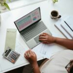 A top-down view of a desk with tax and bookkeeping information, with a calculator and a cup of coffee