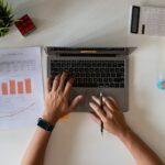 A top-down view of someone working on their MacBook using cash flow management tools for freelancers
