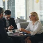 A consultant sits down with two clients having a meeting over coffee discussing the best accounting software for small consulting businesses