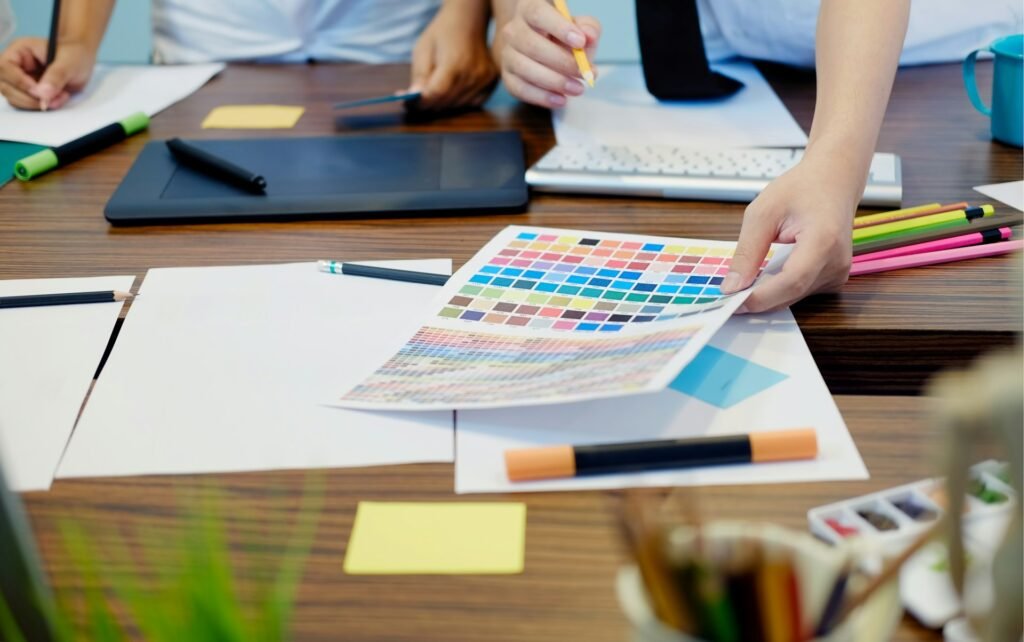 Creative team reviewing colour swatches and design materials at a desk with a graphics tablet