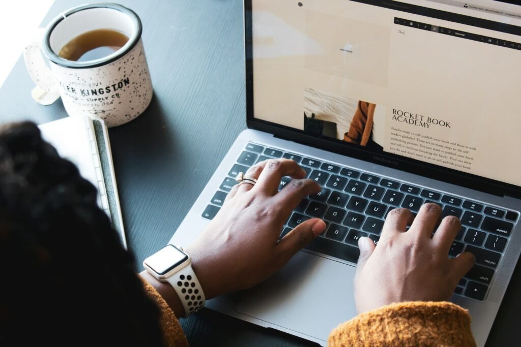 Freelancer using freelance management tools on a MacBook with a cup of tea on a desk