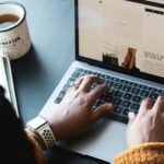 Freelancer using freelance management tools on a MacBook with a cup of tea on a desk