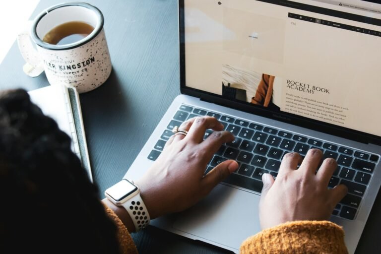 Freelancer using freelance management tools on a MacBook with a cup of tea on a desk