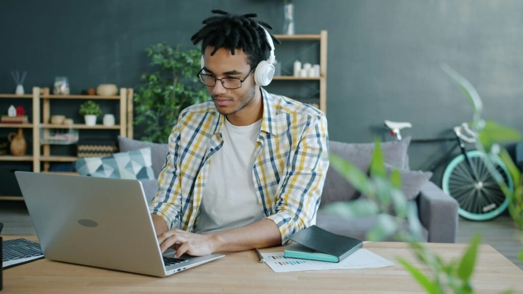 Freelancer working on a laptop with headphones in a home office