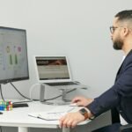 Digital marketing professional working at a dual-monitor setup displaying SEO analytics and a website design. Desktop Accounting Software Without a Subscription is loaded in the background.