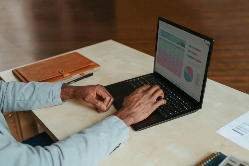 Overhead view of a small business owner working on accounting software with a calculator, invoices and notebook