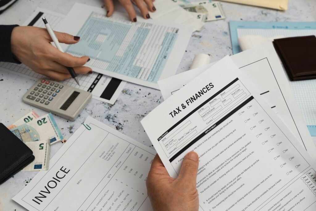 A desk with two people working, filled with tax documents and reports