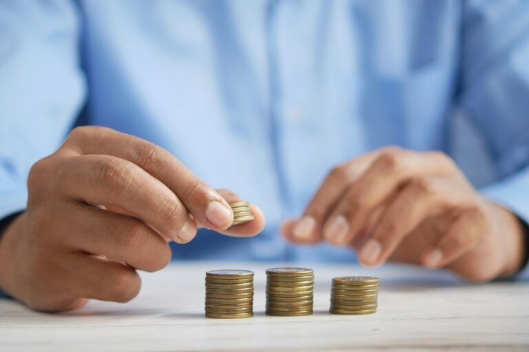A freelancer stacks coins into three piles, illustrating freelance finance strategies, savings goals, and building a financial safety net.