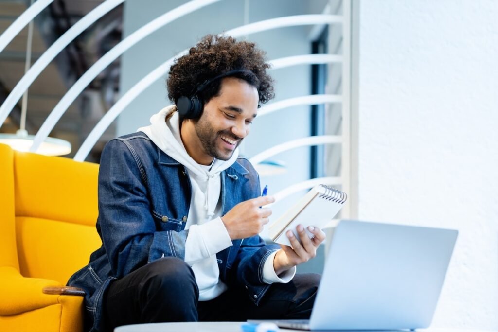 A freelancer researching finance software options for freelancers and consultants while taking notes and working on a laptop in a coworking space.