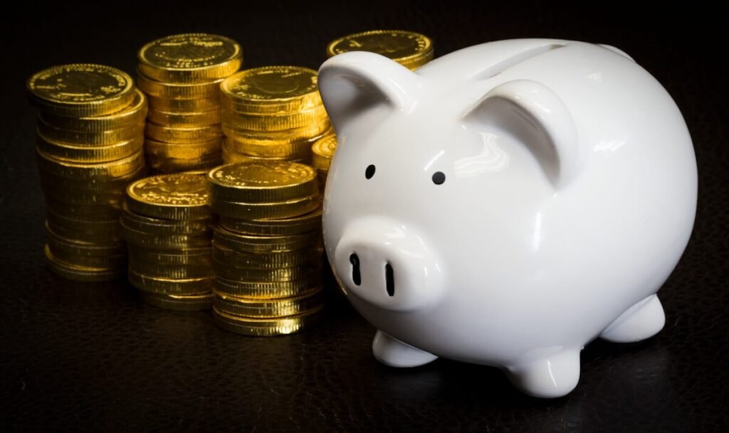 A white piggy bank next to a stack of gold coins, representing retirement savings.
