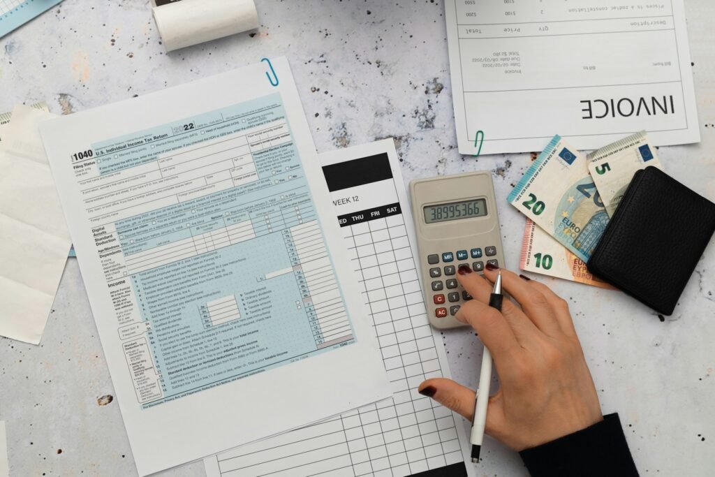 A calculator, pen, and financial paperwork laid out on a desk for tracking business expenses.