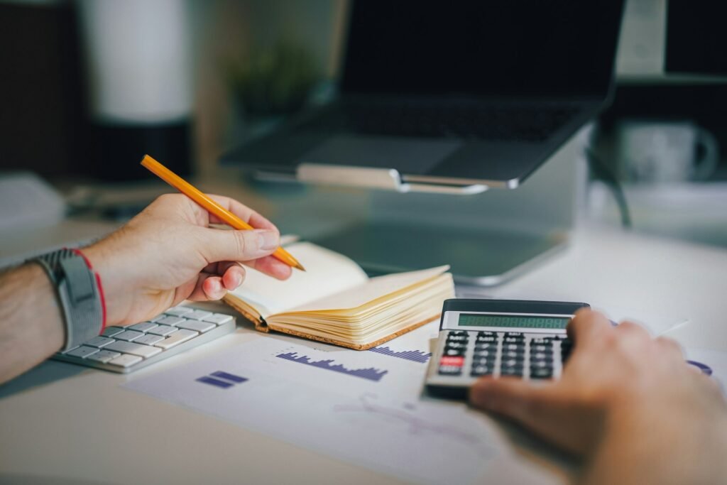 Freelancer using a calculator and notebook to project 12 months of cash flow