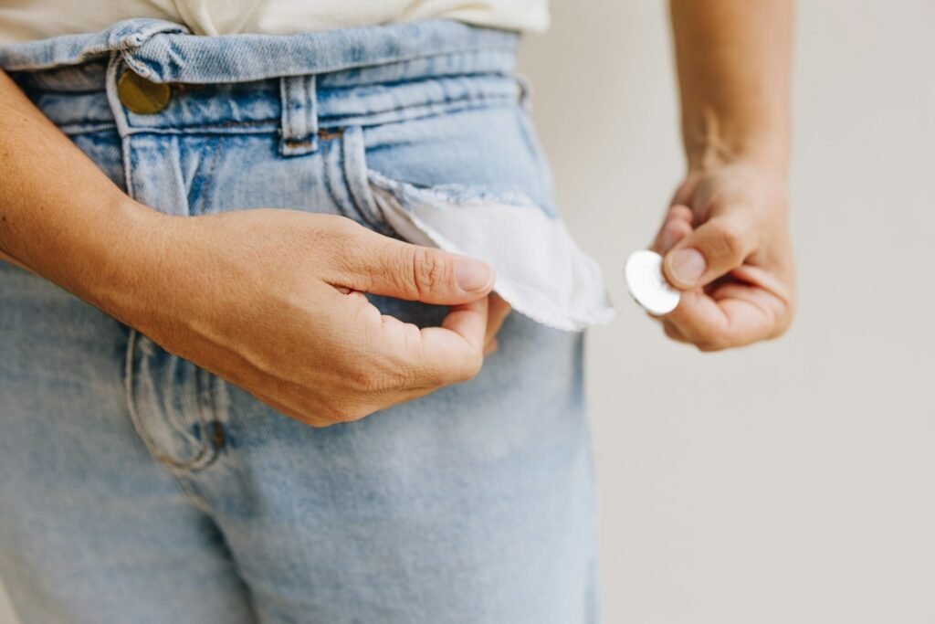 Freelancer turning out empty trouser pockets with a single coin, illustrating freelance cash flow problems