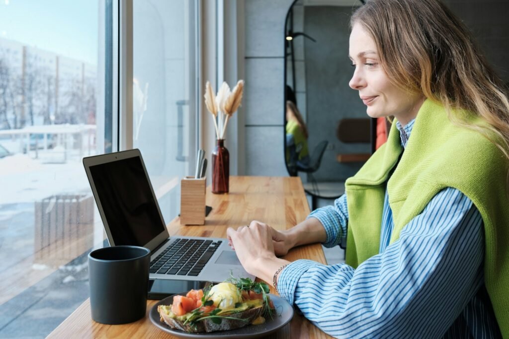 Freelancer working at a laptop beside a plate of food, illustrating why personal meals aren't deductible