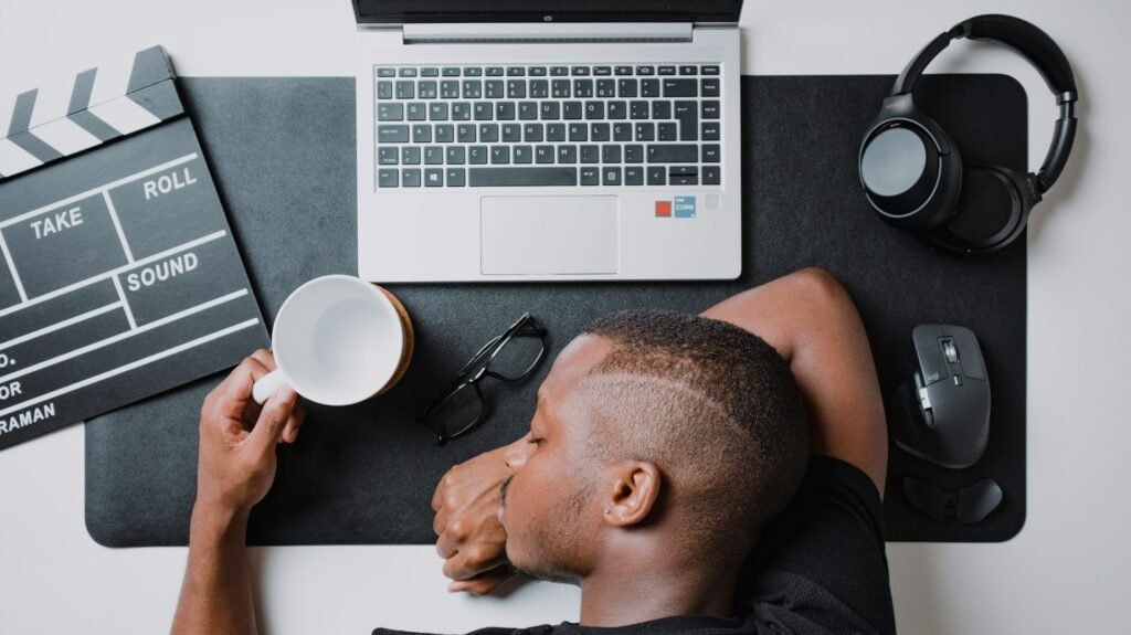 Freelancer working at a desk with a laptop and headphones, illustrating how to maintain a steady workflow as a solo freelancer while looking slightly burned out.