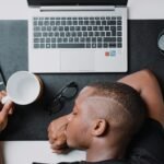 Freelancer working at a desk with a laptop and headphones, illustrating how to maintain a steady workflow as a solo freelancer while looking slightly burned out.