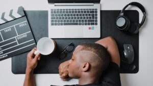 Freelancer working at a desk with a laptop and headphones, illustrating how to maintain a steady workflow as a solo freelancer while looking slightly burned out.