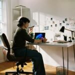 Freelancer working at a sunlit home-office desk by the window, illustrating how to stay focused when working from home.