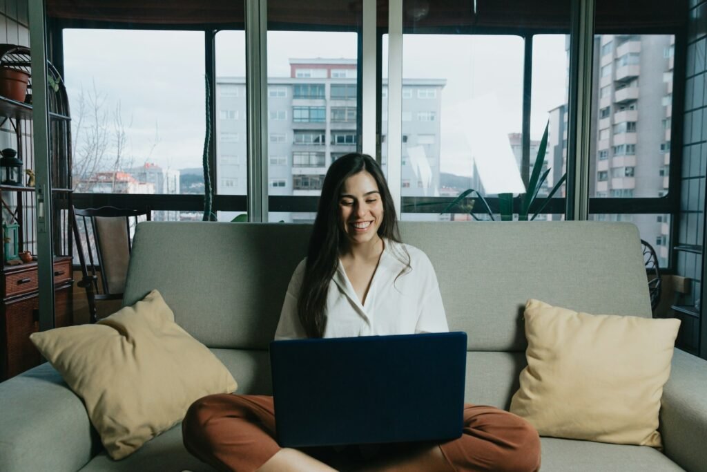 Freelancer working on a laptop from her couch, setting up a system to prevent cash flow problems