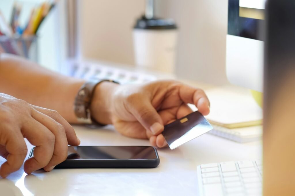 Man paying online with a credit card and phone, illustrating how clients settle freelance invoices