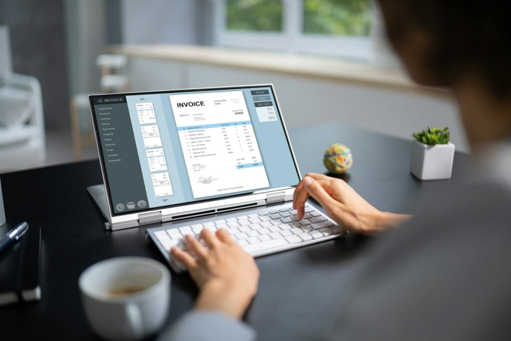 Someone writing out an invoice on their laptop over coffee