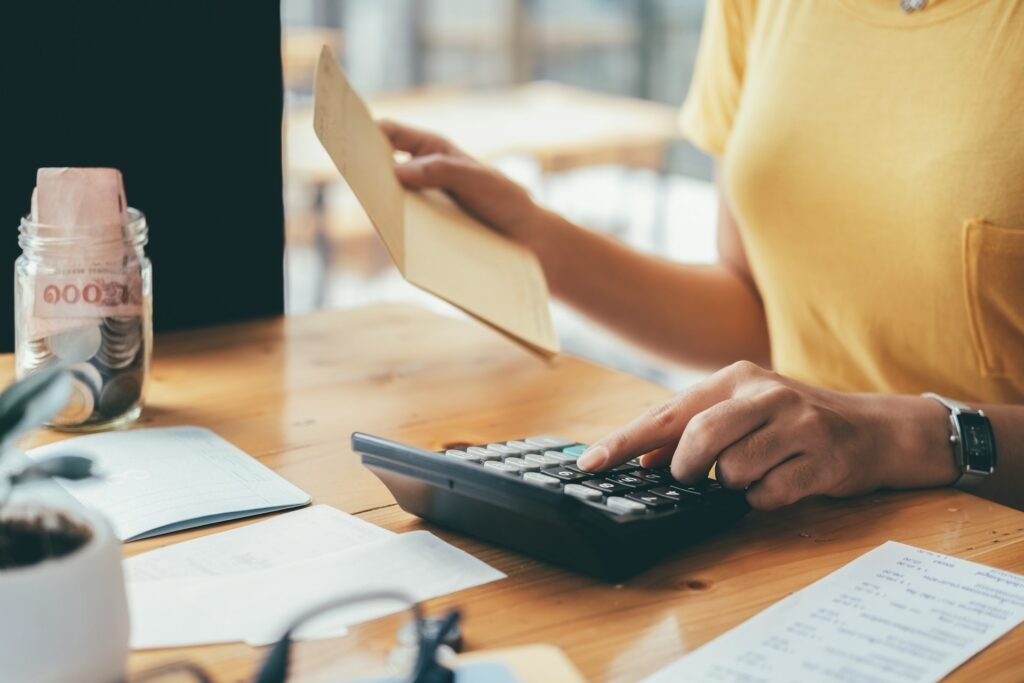 Accountant calculating a freelancer tax bill with cash and a calculator on a desk