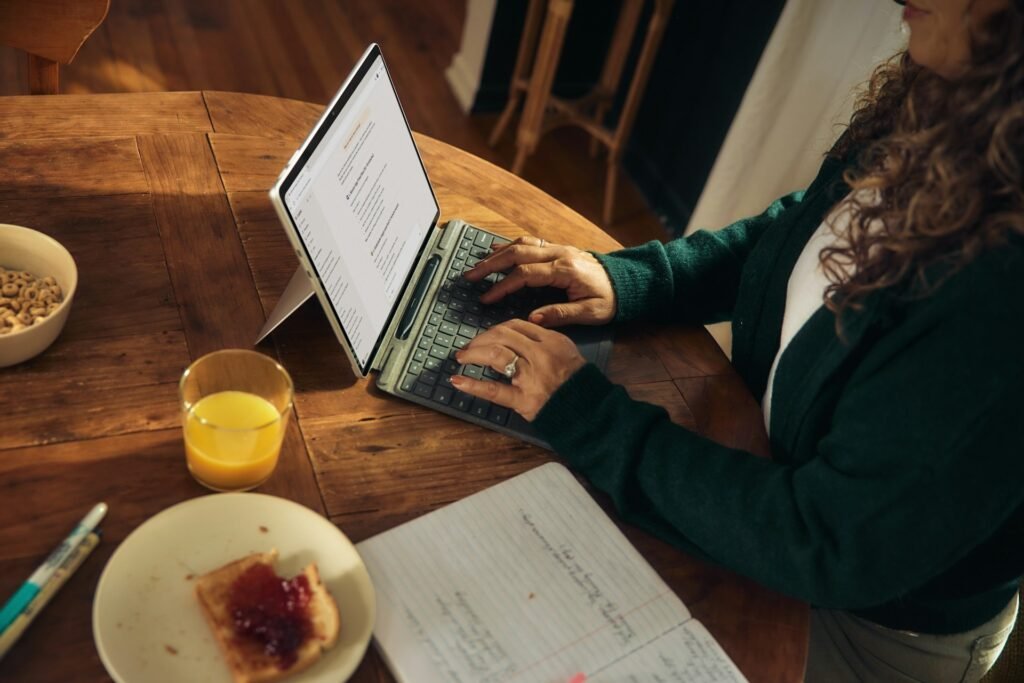 A female freelance works on sending out emails and invoices or her laptop over breakfast