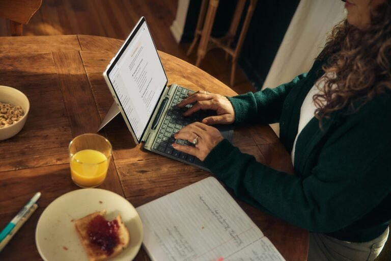 A female freelance works on sending out emails and invoices or her laptop over breakfast