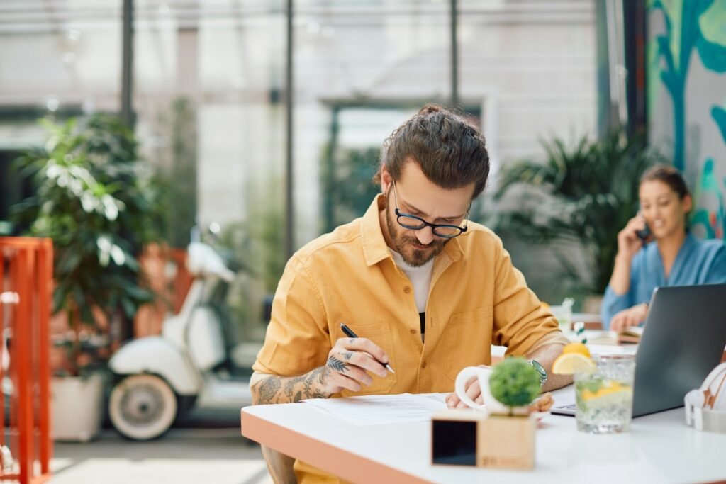 Freelancer comparing an invoice and a quote while working in a cafe