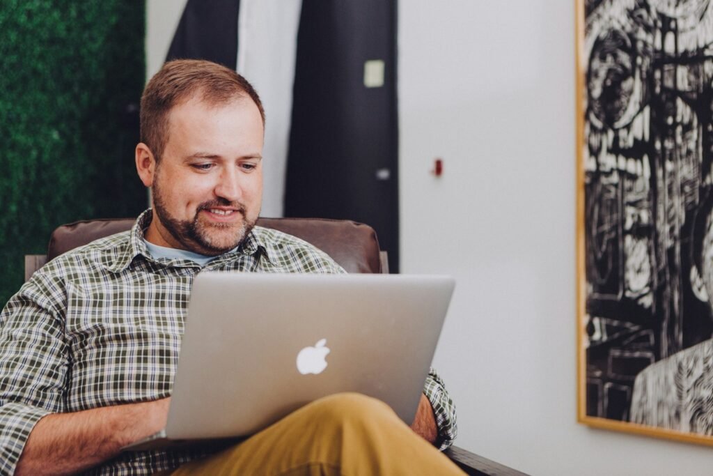 Freelancer smiling at a MacBook after setting up automatic invoice payment reminders