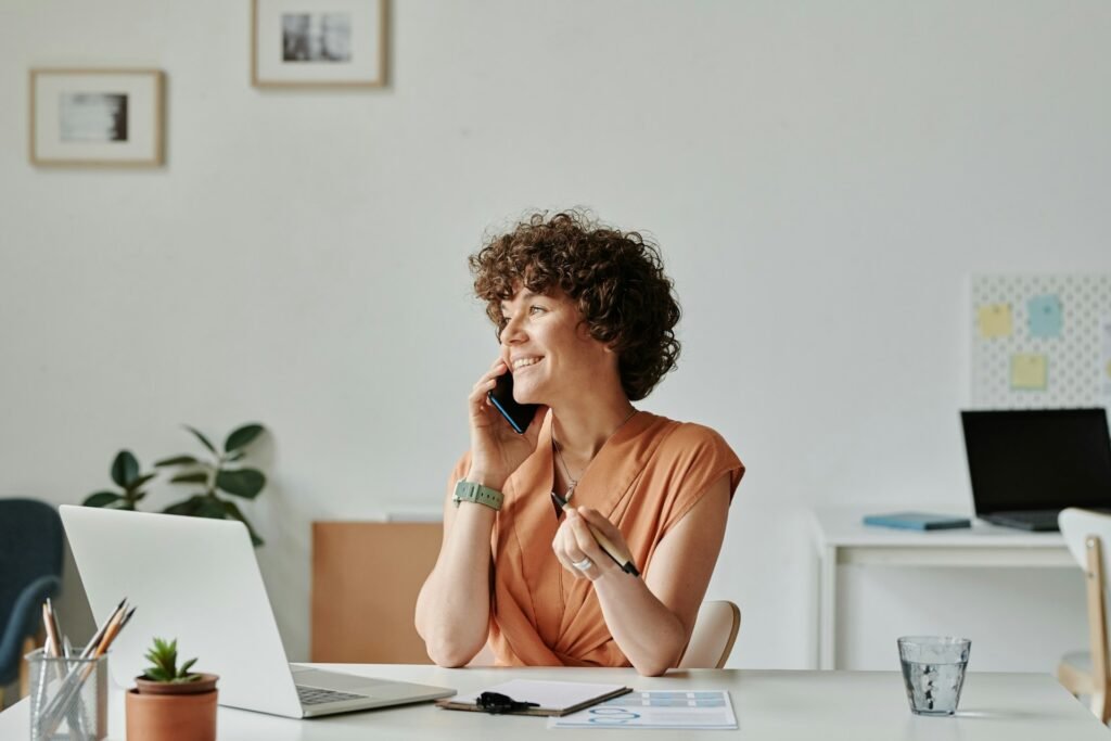 Freelancer smiling on the phone at her desk after signing a client contract