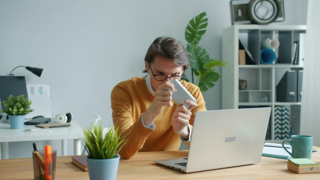 Freelancer drinking coffee at a desk while tracking billable hours on a laptop