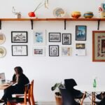 Freelancer working on a laptop at a café table with a gallery wall behind