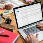 Freelancer working through a full email inbox on a laptop at a cluttered desk