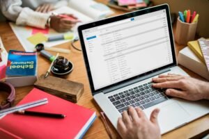 Freelancer working through a full email inbox on a laptop at a cluttered desk