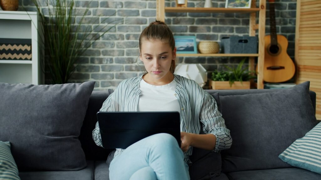 Freelancer working through her daily task list on a laptop from the couch