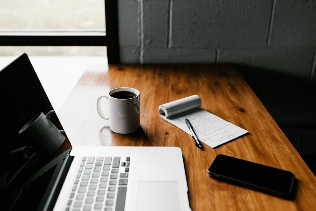 Laptop, phone, and coffee on a desk showing a freelancer's AI to-do list setup