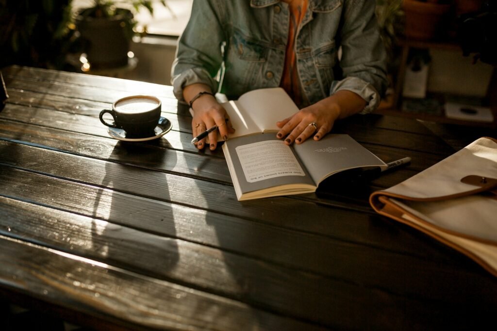 Open notebook and pen on a dark café table beside a coffee cup