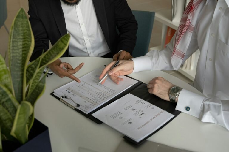 Two people reviewing a freelance contract template with papers and a pen on the table