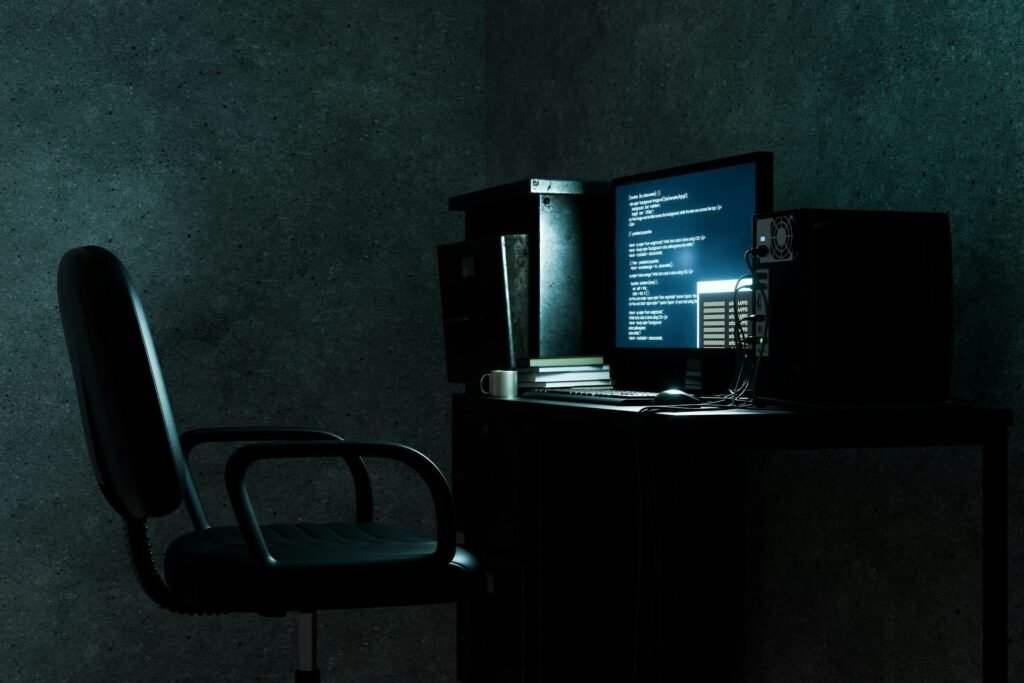 Desktop computer displaying code for a self-hosted freelance set up on screen in a dimly lit room