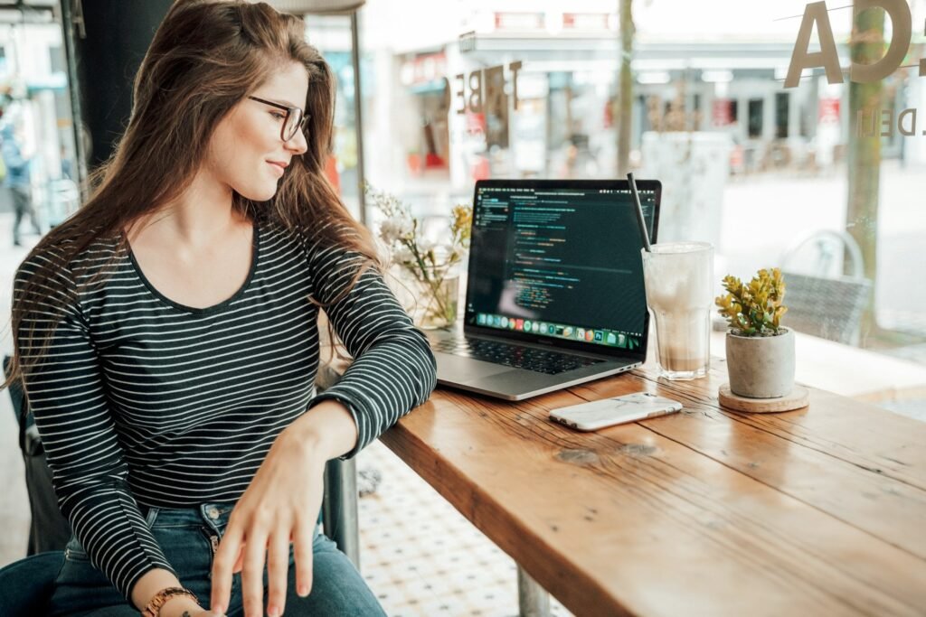 Freelancer at a café table beside a laptop displaying code