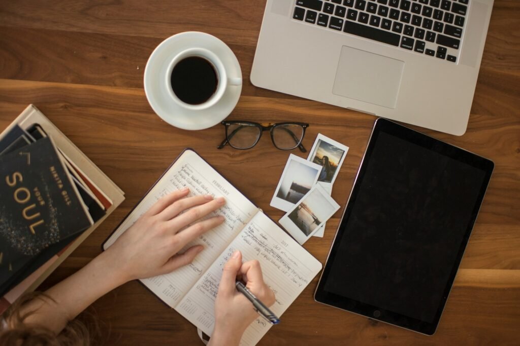 Freelancer mapping out the month ahead in a paper planner, laptop and coffee alongside