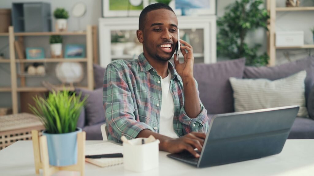 Freelancer on a phone call while working at a laptop at home