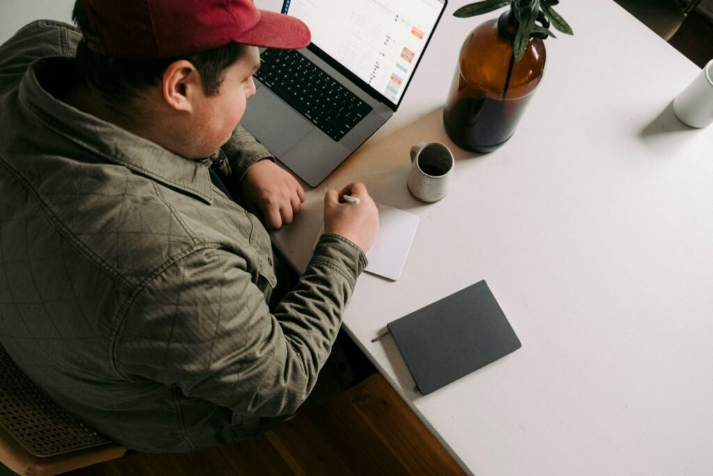 Freelancer planning workload management in a notebook beside an open laptop and coffee