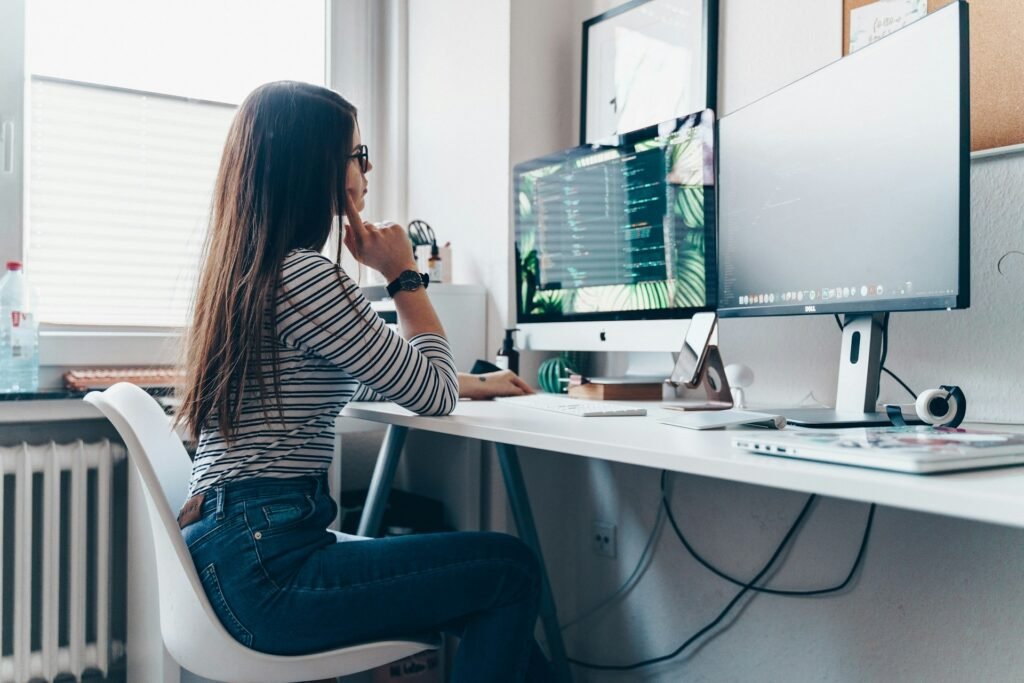 Freelancer sitting at a desk looking at two monitors with code on screen